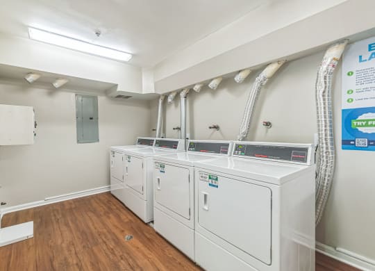 a laundry room with four washers and dryers and a row of washing machines at Sanger Place, Lorton, 22079