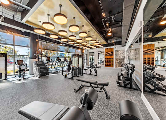 a gym with weights and cardio equipment on the floor and a view of a building at South and Hollis, North Carolina