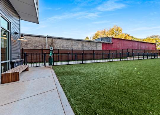 the yard is fenced in with a green lawn and a brick wall