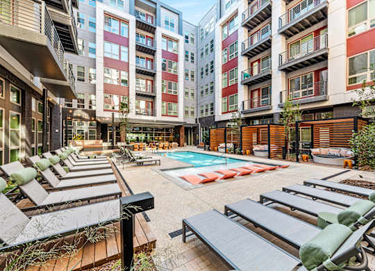 an open courtyard with lounge chairs and a pool in an apartment building