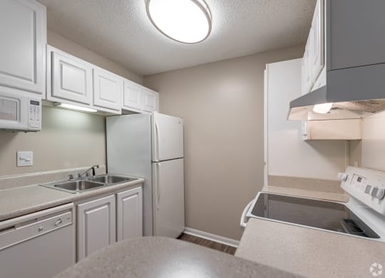 a kitchen with white cabinets and a sink and a refrigerator at Alexander Ridge Apartments, Canton , GA 30114