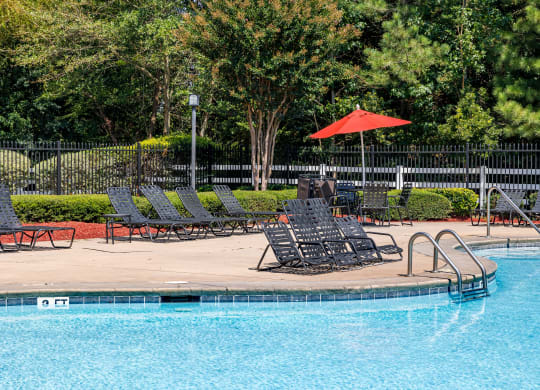 a swimming pool with lounge chairs and an umbrella at Alexander Ridge Apartments, Georgia
