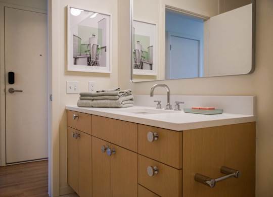 A bathroom with a sink, mirror, and cabinets.