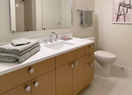 A bathroom with a toilet, sink, and mirror.