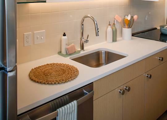 A kitchen with a sink, refrigerator, and wooden cabinets.