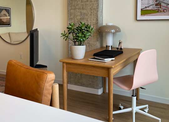A room with a desk, chair, and mirror.