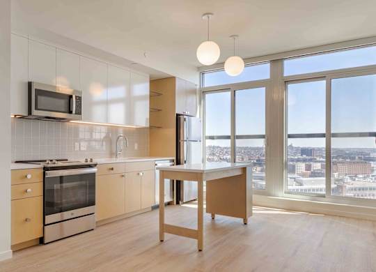 A kitchen with a microwave above the stove and a table in front of a window.