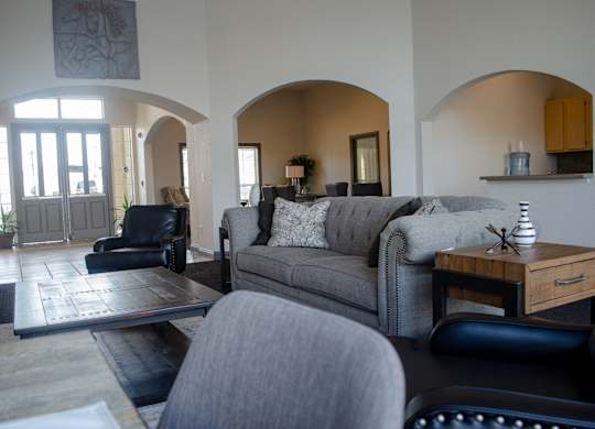 A living room with a grey couch and a black chair at Arrowhead Ridge Apartments, New Mexico