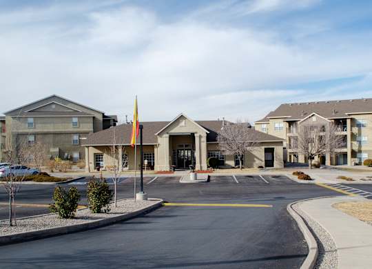 A large building with a flag in front of it at Arrowhead Ridge Apartments, Rio Rancho, NM