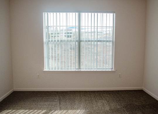 A room with a window and a carpeted floor at Arrowhead Ridge Apartments, Rio Rancho, NM