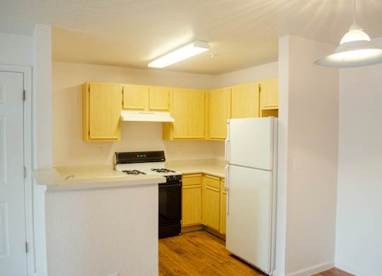 A kitchen with yellow cabinets and white appliances at Arrowhead Ridge Apartments, Rio Rancho, NM, 87124