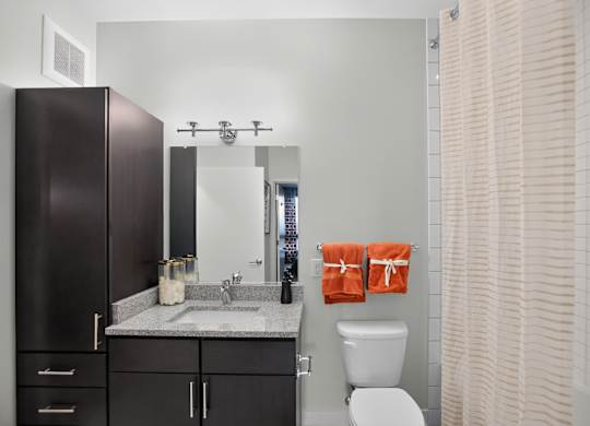 A bathroom with a toilet, sink, and a mirror.