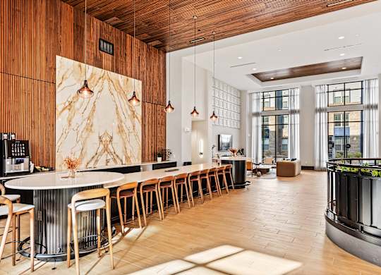 A modern kitchen with a long bar and wooden floors at the Preston Ridge Clubhouse in Cary, NC.