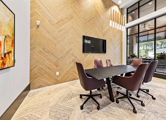 A conference room with a table and chairs and a TV on the wall at Preston Ridge Apartments.