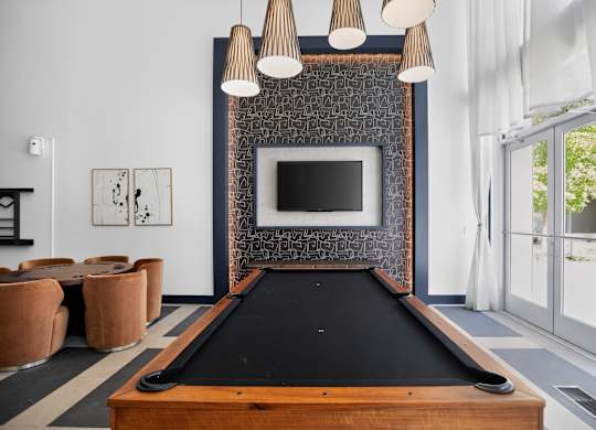 A pool table is in the middle of a room with a television and a fireplace.