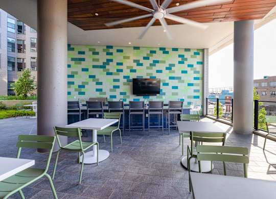 a patio with tables and chairs and a wall with a television at Coda at Bryant Street, Washington