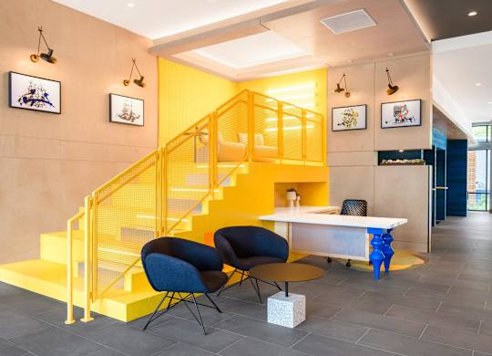 a yellow staircase in a lobby with chairs and a table at Coda at Bryant Street, Washington DC