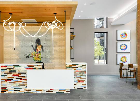 a reception area with a white reception desk and a mosaic wall at Coda at Bryant Street, Washington, DC 20002