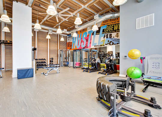 a gym with weights and cardio machines and a large wall with a sign on it at Coda at Bryant Street, Washington