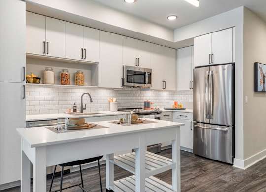 a kitchen with white cabinets and a white island and a refrigerator at Coda at Bryant Street, Washington