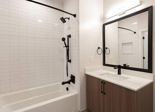 a bathroom with a white tub and a sink and a mirror at Coda at Bryant Street, Washington, DC 20002