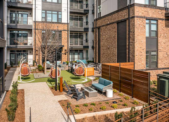 A courtyard with a white fence and a green lawn at Hawkins Press Apartments, Charlotte, NC