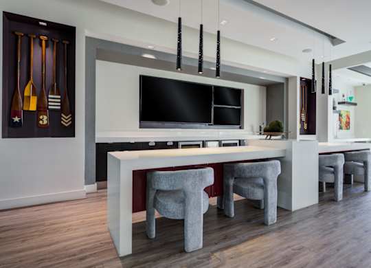 A modern kitchen with a white countertop and grey chairs.