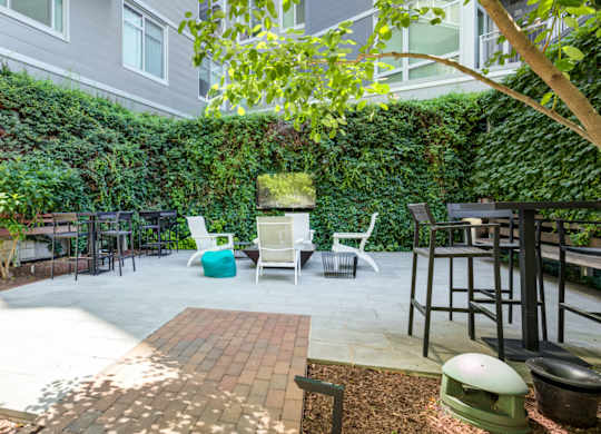 A patio with a white table and chairs surrounded by a green wall.