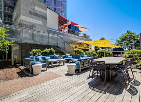 A wooden deck with a table and chairs in the foreground and a building in the background.