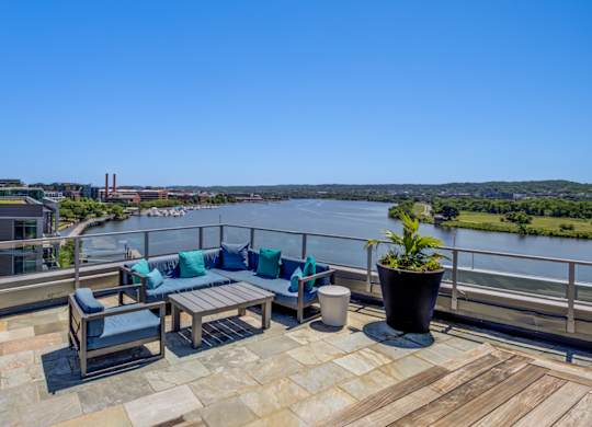 A balcony with a table and chairs overlooking a river.