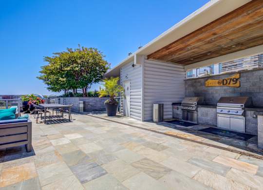 A patio with a grill and a table with chairs.