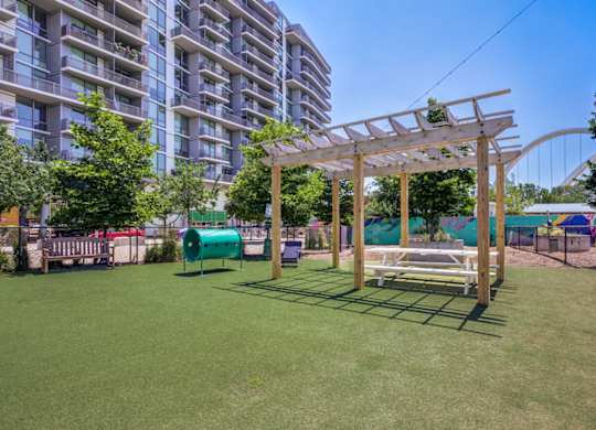 A wooden pergola is in the middle of a grassy area.