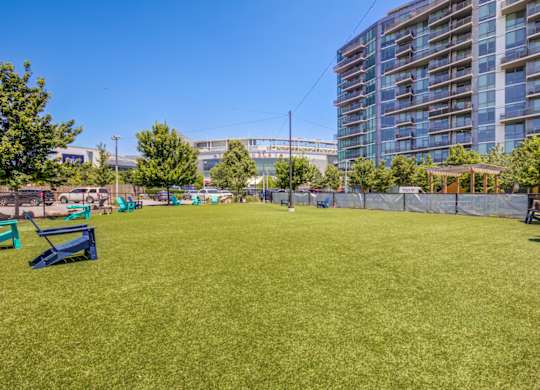 A grassy field with benches and a fence in the foreground and a large building in the background.