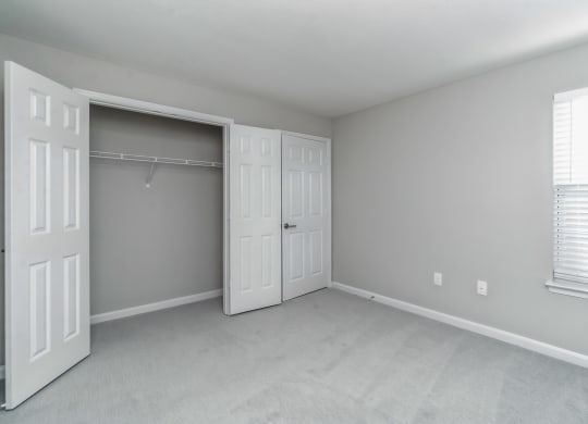 an empty bedroom with white doors and a closet at The Fields at Lorton Station, Virginia