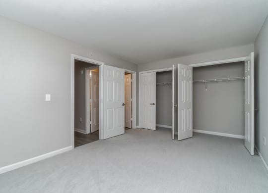 an empty bedroom with three closets and three doors