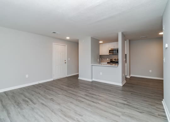 the living room and kitchen of an apartment with wood flooring at The Fields at Lorton Station, Virginia