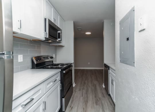 an empty kitchen with white cabinets and a black stove at The Fields at Lorton Station, Lorton, Virginia