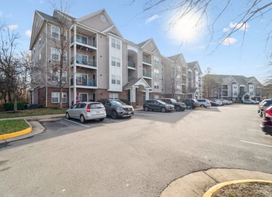 a large apartment building with cars parked in front of it at The Fields at Lorton Station, Lorton, VA, 22079