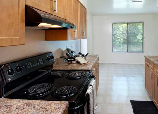 A kitchen with a black stove top oven and wooden cabinets.
