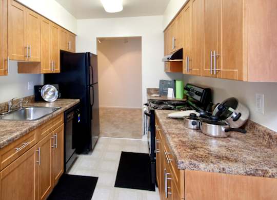 A kitchen with brown cabinets and granite countertops.