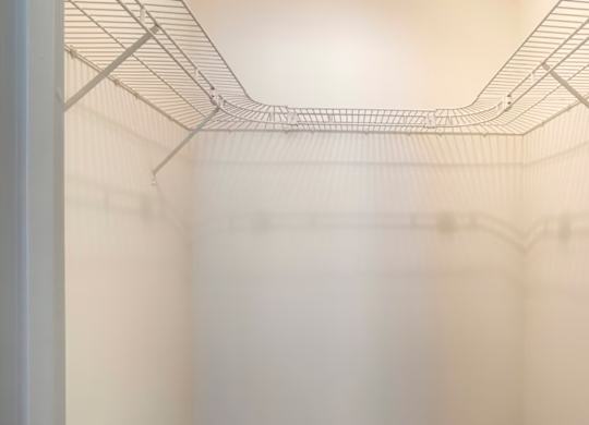 Empty wire shelving in a white fridge.
