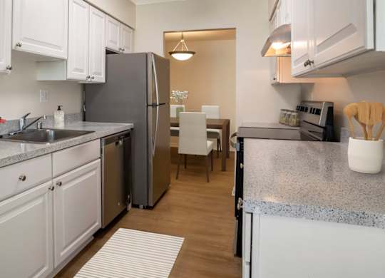 A kitchen with white cabinets and a grey granite countertop.