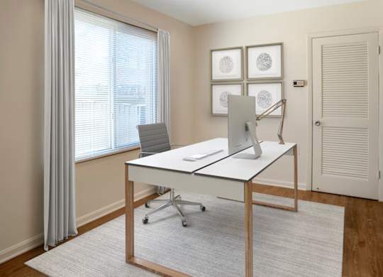 A white desk with a laptop and a phone on it in a room.