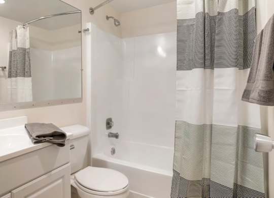 A white bathroom with a toilet, sink, and shower.