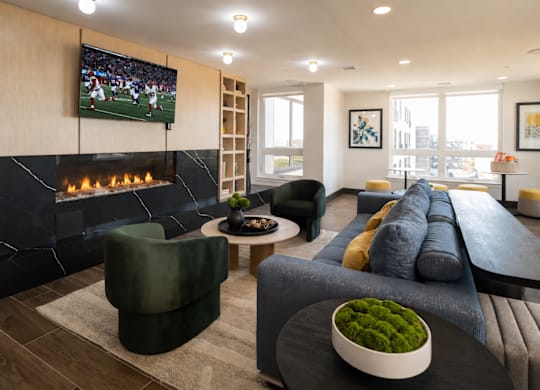 A modern living room with a fireplace and a television displaying a football game.