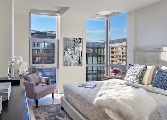 A bedroom with a large bed and a chair by a window.