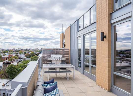A balcony with a table and chairs overlooking a cityscape.