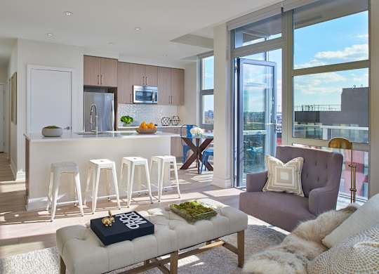 A modern living room with a bar area and a view of the city.