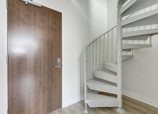 A white spiral staircase with a wooden door.