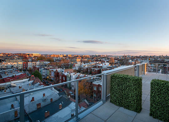 A balcony overlooks a cityscape at sunset.
